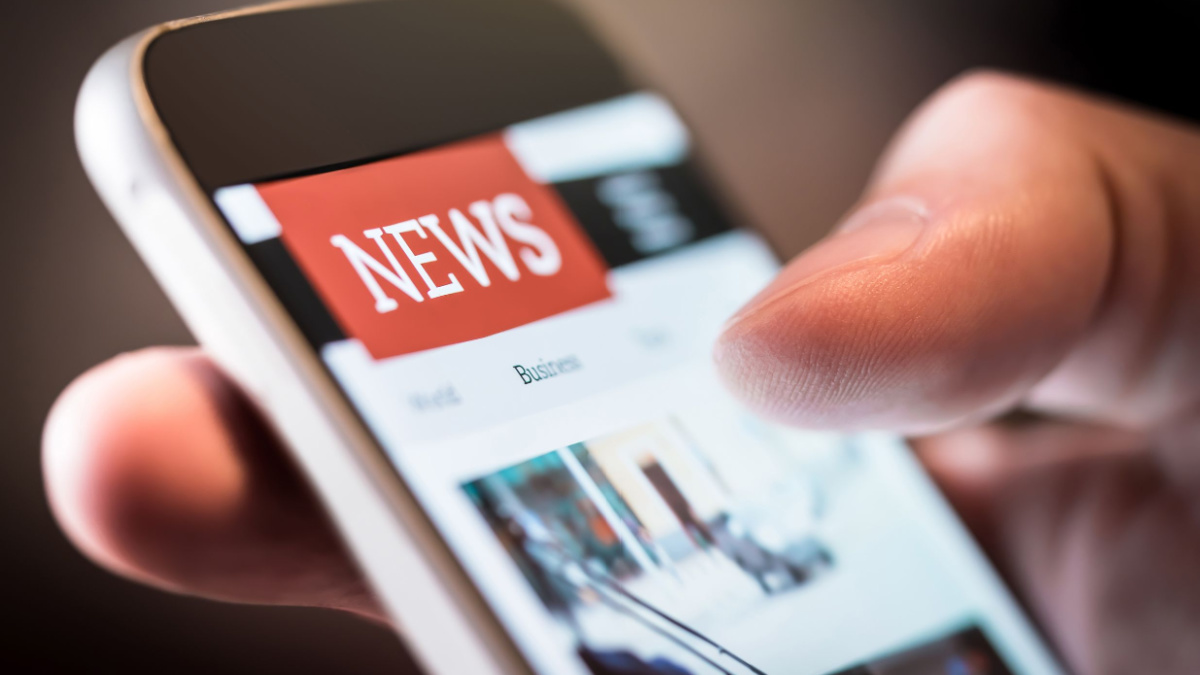 Online news in mobile phone. Close up of smartphone screen. Man reading articles in application. Hand holding smart device. Mockup website. Newspaper and portal on internet.