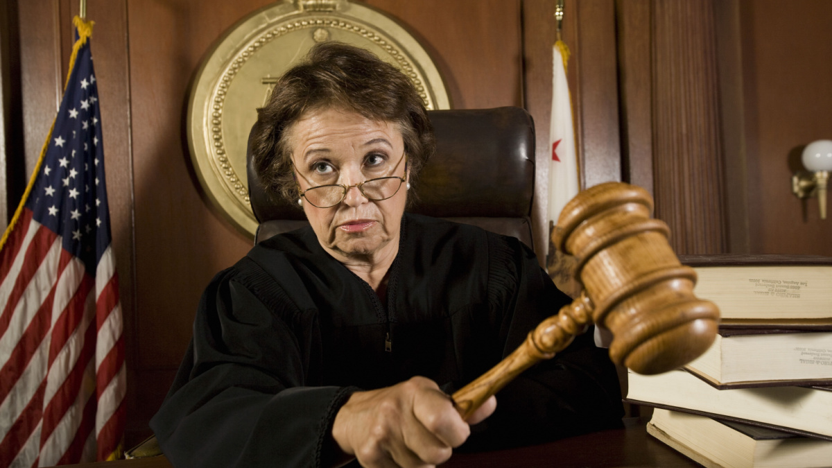 Senior Caucasian judge holding mallet in courtroom.