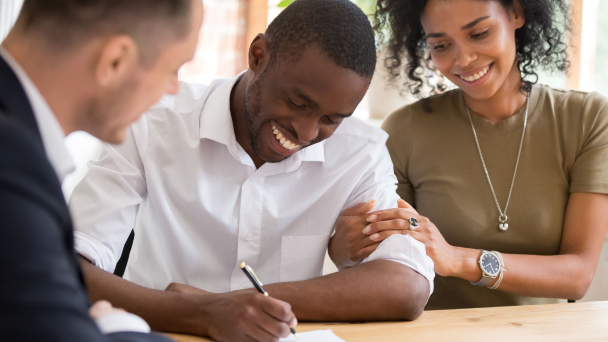 Happy african black family couple customers renters tenants sign mortgage loan investment agreement or rental insurance contract meeting realtor lender landlord making real estate sale purchase deal.