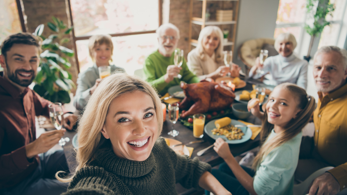 Photo of big family sit feast dishes table around roasted turkey multi-generation relatives making group selfies raising wine glasses juice in living room indoors.