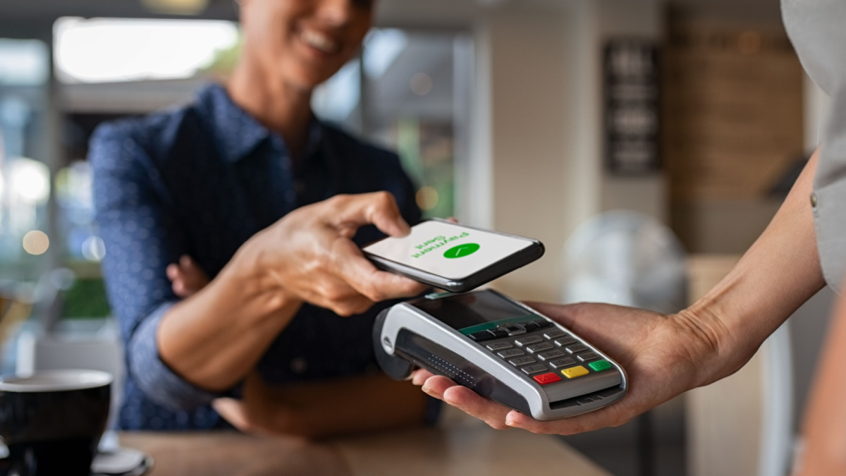 Woman paying bill through smartphone using NFC technology in a restaurant.