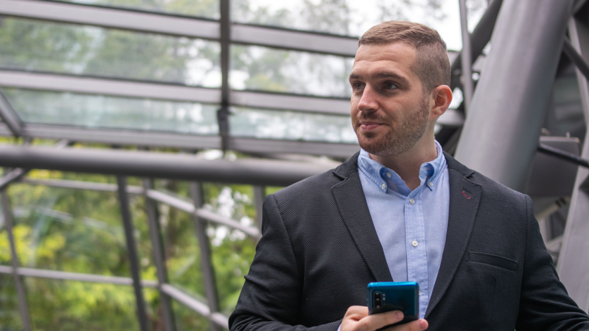 Photo of a young and attractive business man checking his phone. Wearing smart casual clothes. Entrepeneur style.