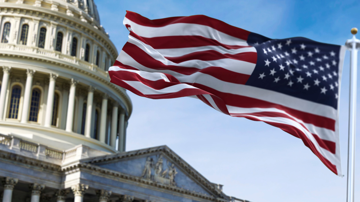 American flag waving with the US Capitol Hill in the background.