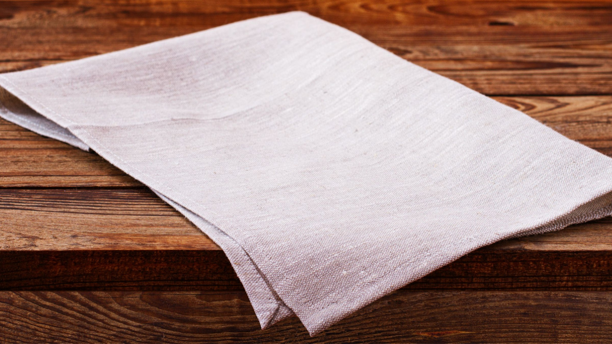 Empty wooden deck with table cloth, napkin over wall background.
