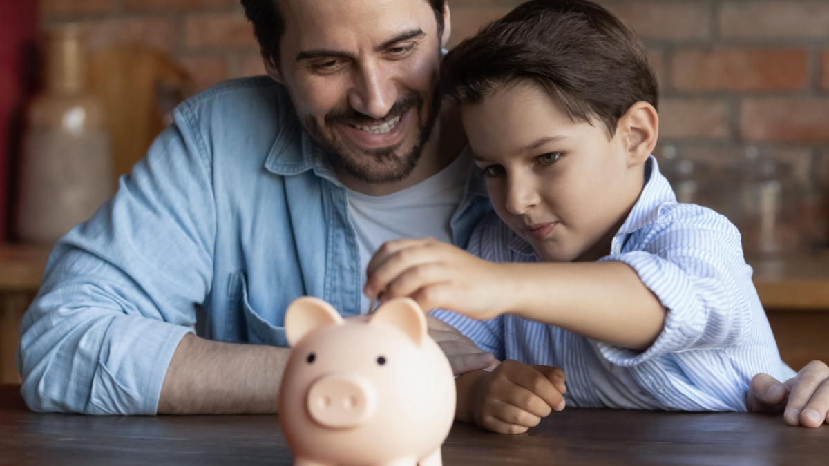 Happy dad teaching smart little son to save and invest money, encourage kid for accounting, investment, planning future budget.