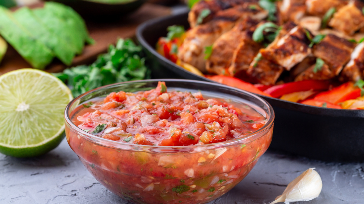 Tex-Mex cuisine salsa Asada sauce with roasted vegetables, served with Chicken Fajitas, horizontal.