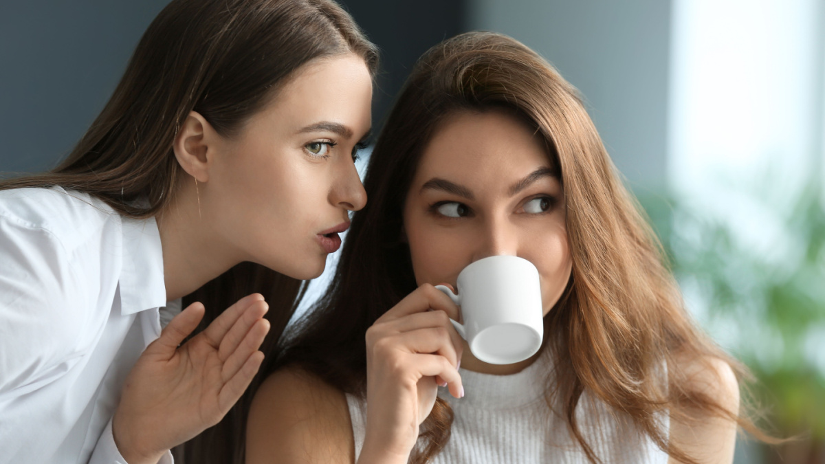 Female colleagues gossiping in office.