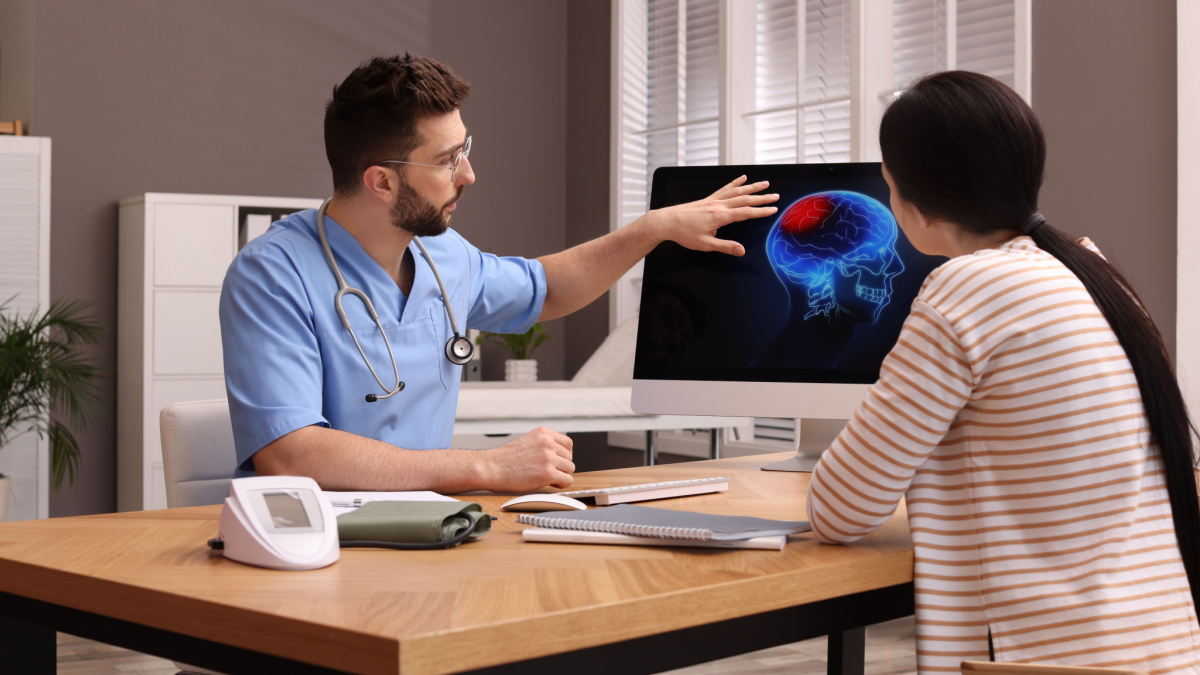 Neurologist showing brain scan to young woman in clinic.