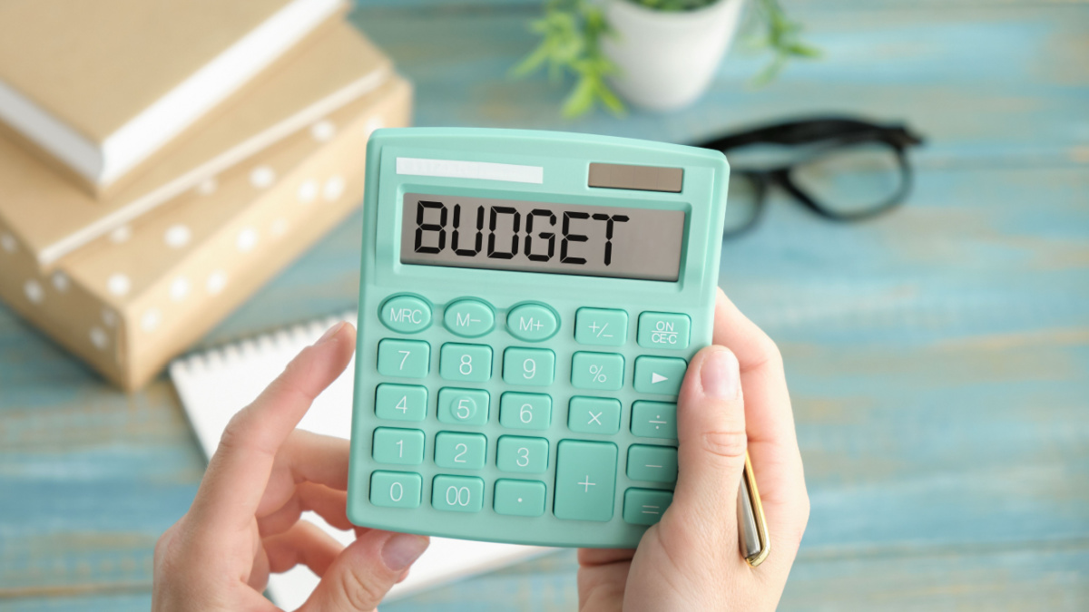 Calculator with the word BUDGET on the display. Pen, eyeglasses and notepad on the diagrams. Concept photo.