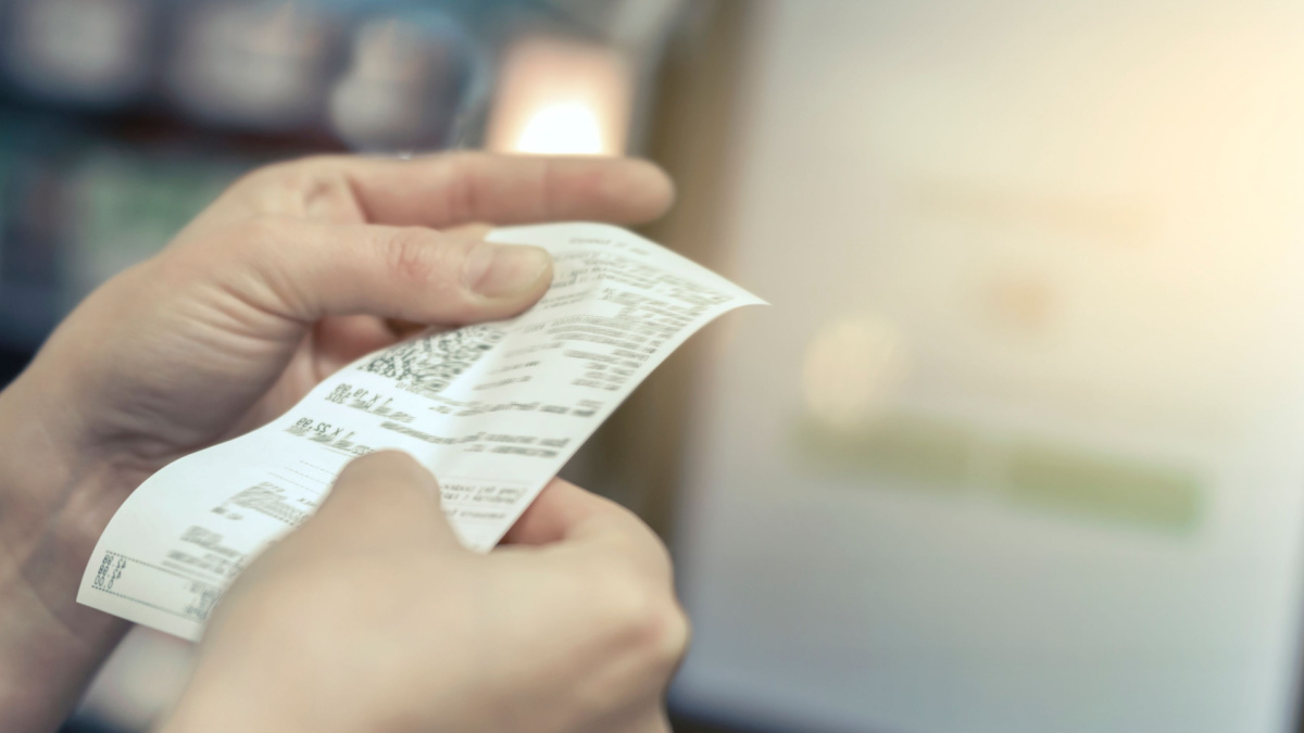 the girl looks at the receipt in the store.