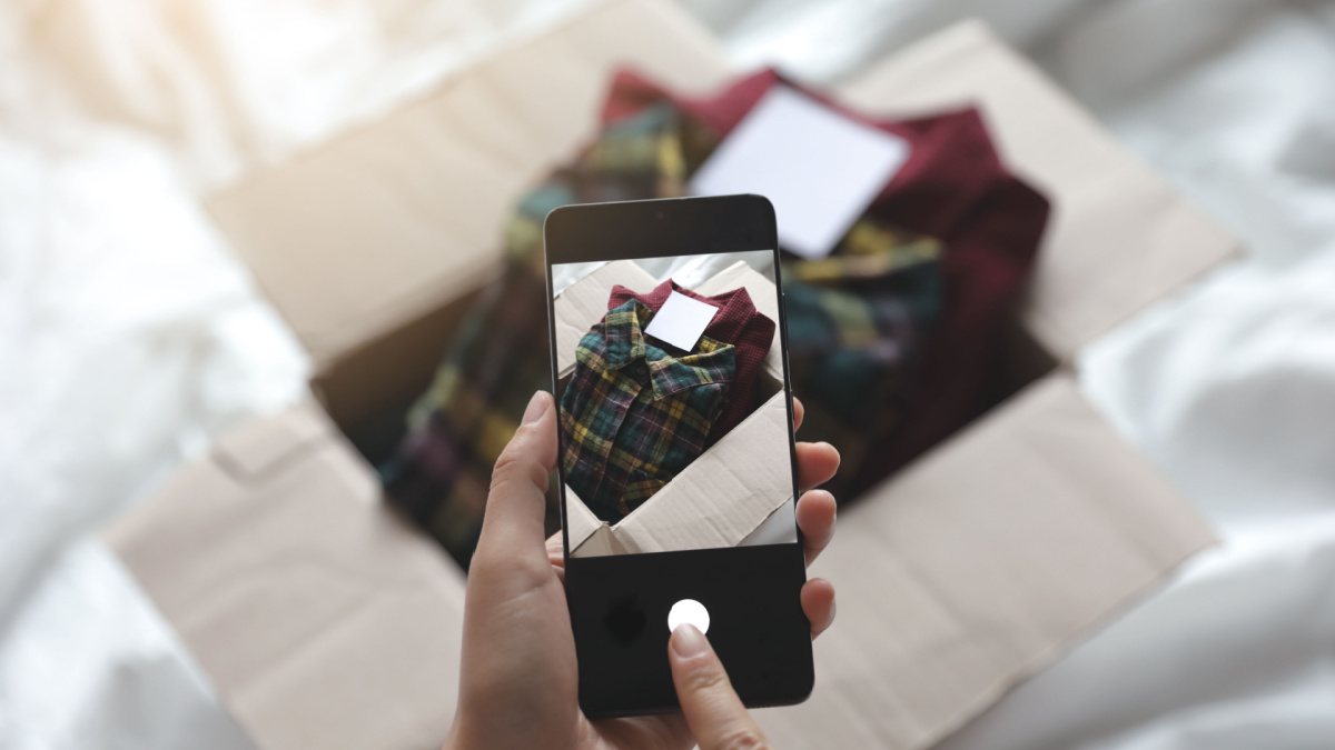 reseller is photographing used clothes in a box for online Selling.