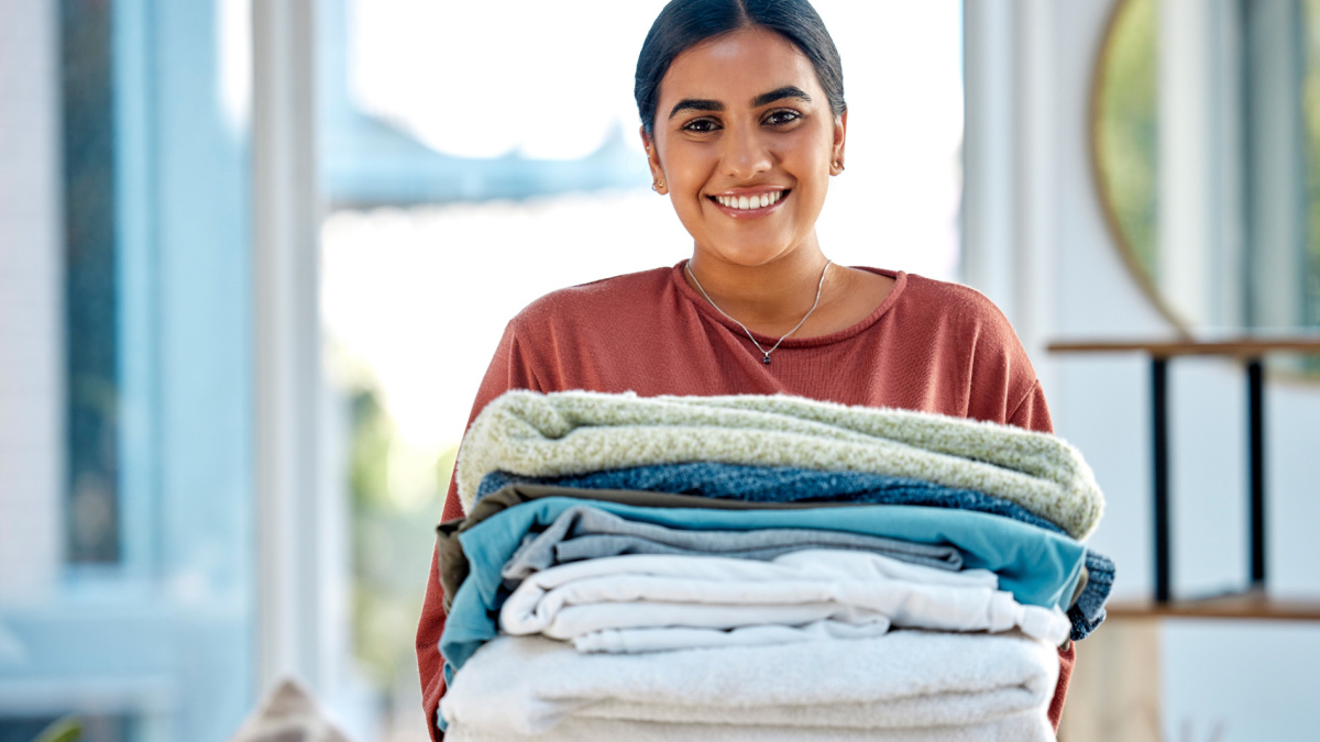 Portrait, cleaning or woman with laundry or happy smile after washing clothes or towels in cleaning services.