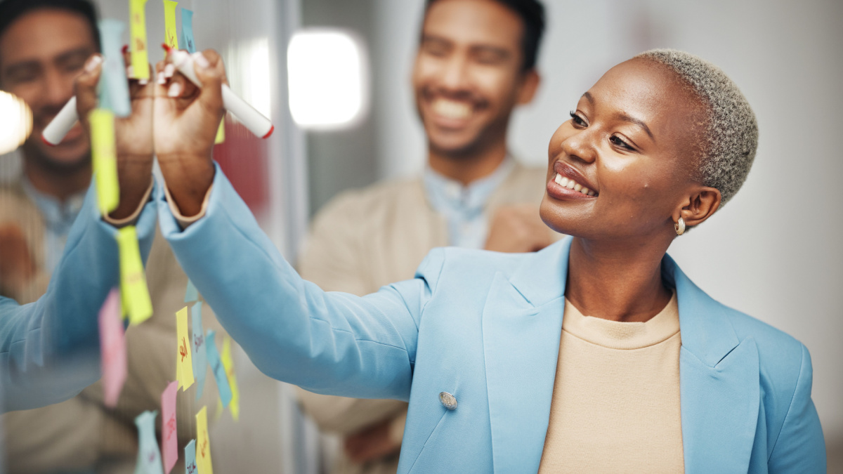 Businesswoman, planning and writing idea in meeting, calendar or agenda, sticky note or innovation.