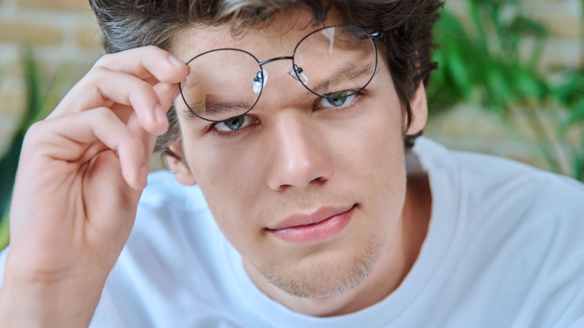 Close-up face of young handsome guy wearing glasses looking at camera.