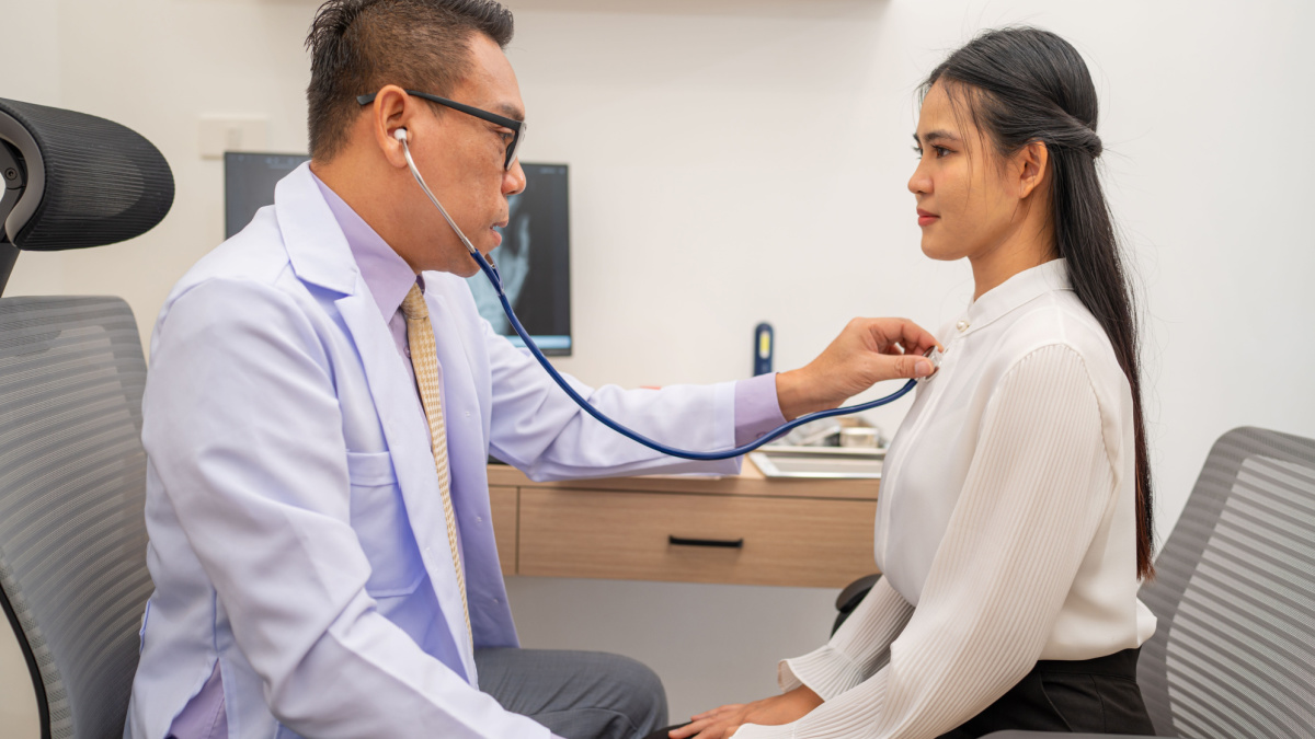 Doctor using stethoscope to listen heartbeat of elderly patient. young Asian woman to detect abnormal heart rates from insufficient rest.