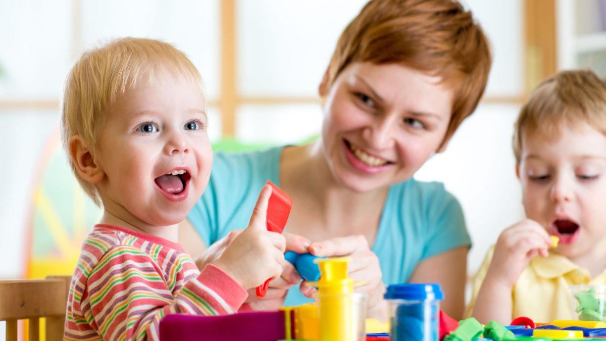 woman teaches kids handcraft at kindergarten or playschool.