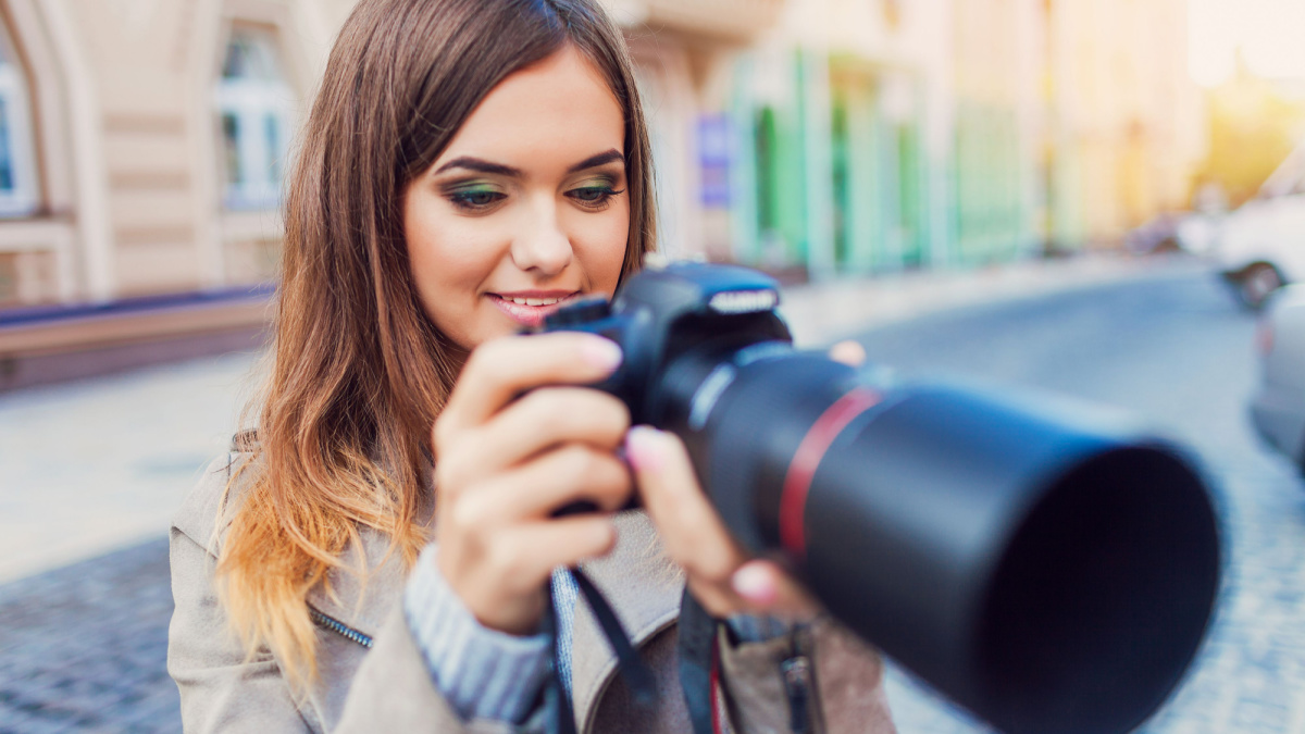 Happy woman on vacation photographing with a dslr camera on the city street.