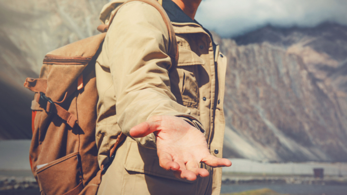 Young travel man lending a helping hand in outdoor mountain scenery.