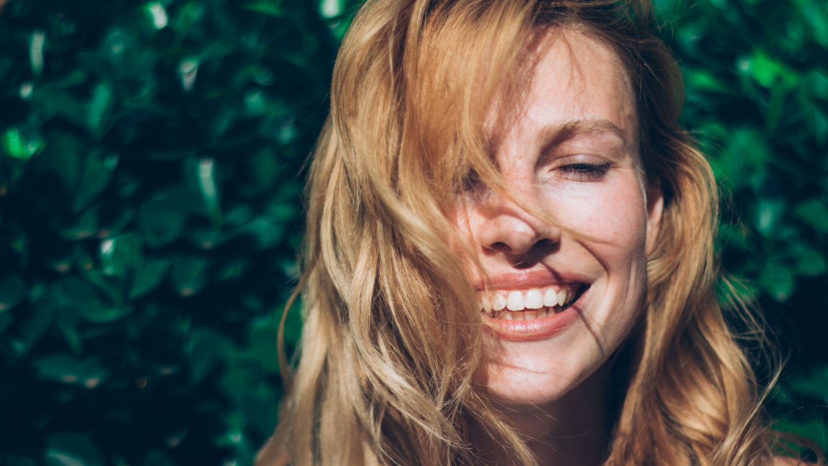 Closeup photo of a young cute woman in nature - sunshine face.