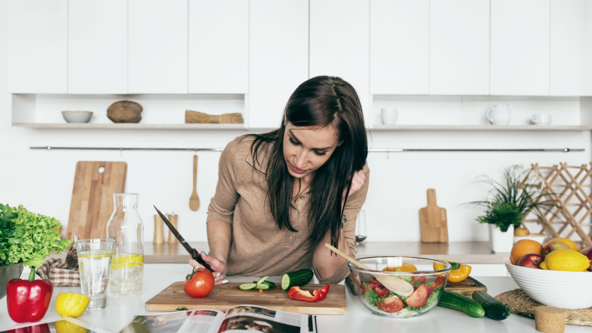 Woman reading recipe for simple summer salad in cookbook. Simple healthy food concept