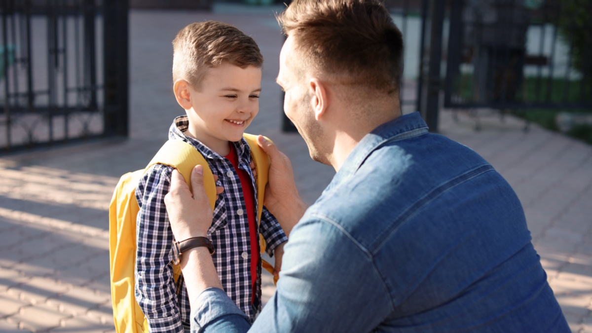 Young man saying goodbye to his little child near school.