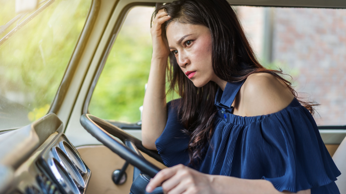 stressed woman sitting inside a vintage car.