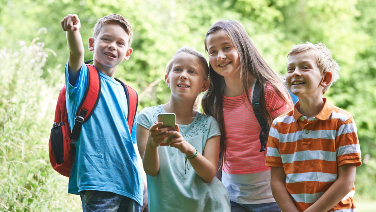 Group Of Children Geocaching In Woods