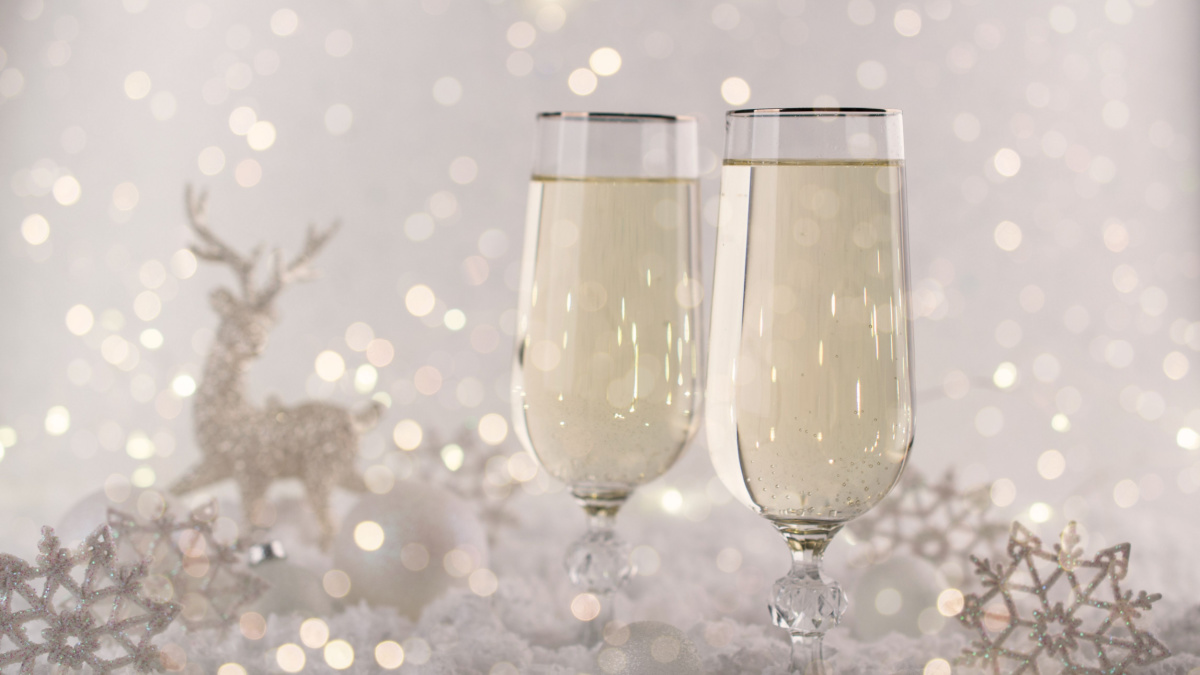 New Year and Christmas Celebration .Two Champagne Glasses and Holiday decoration. Beautiful shiny place setting for Christmas. Sparkler background, winter season.