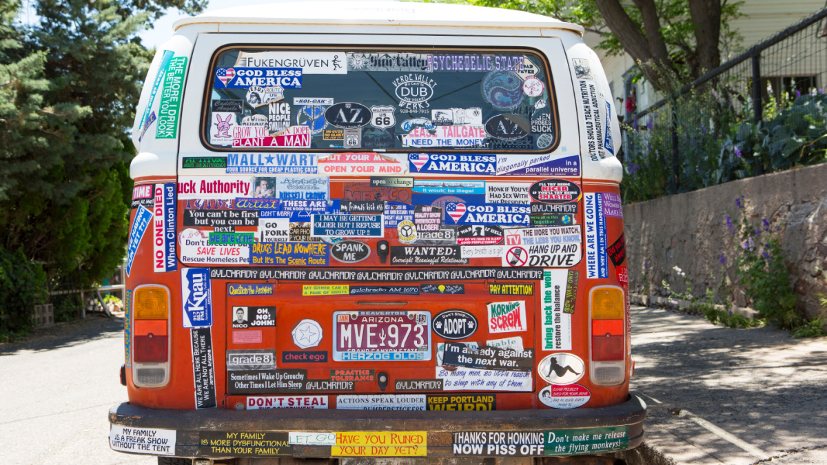 A Volkswagen bus covered in bumper stickers is parked on a side street in the historic mining town of Jerome Arizona.