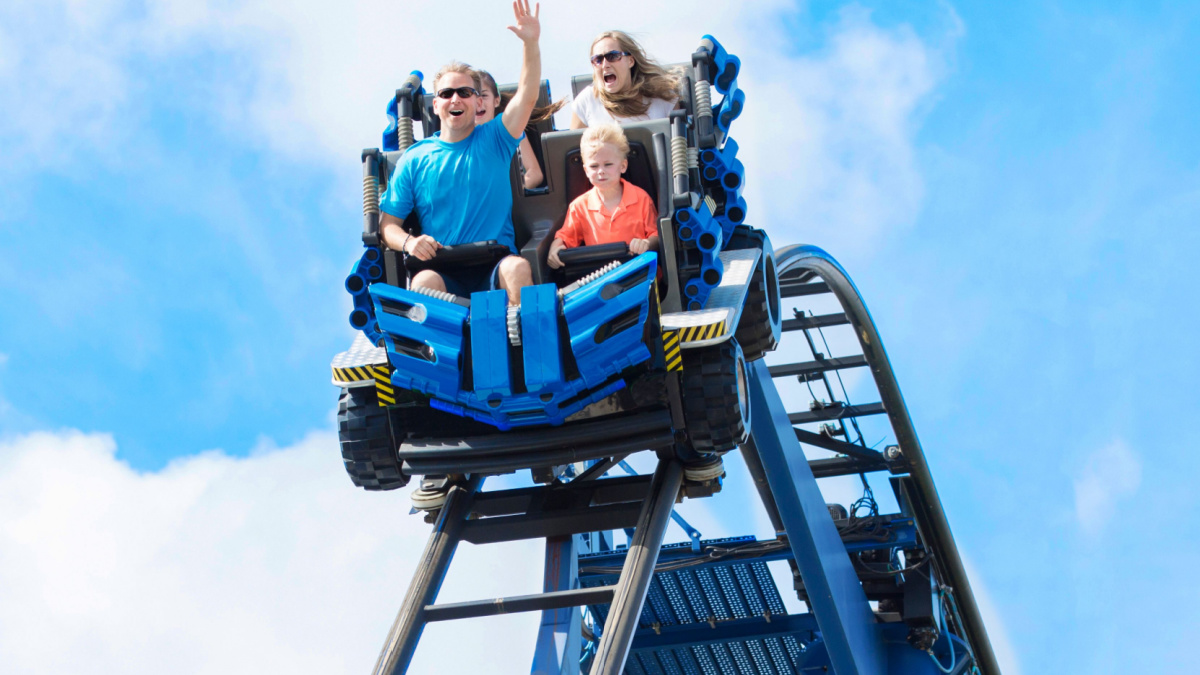 Young family having fun riding a rollercoaster at a theme park. Screaming, laughing and enjoying a fun summer vacation together.