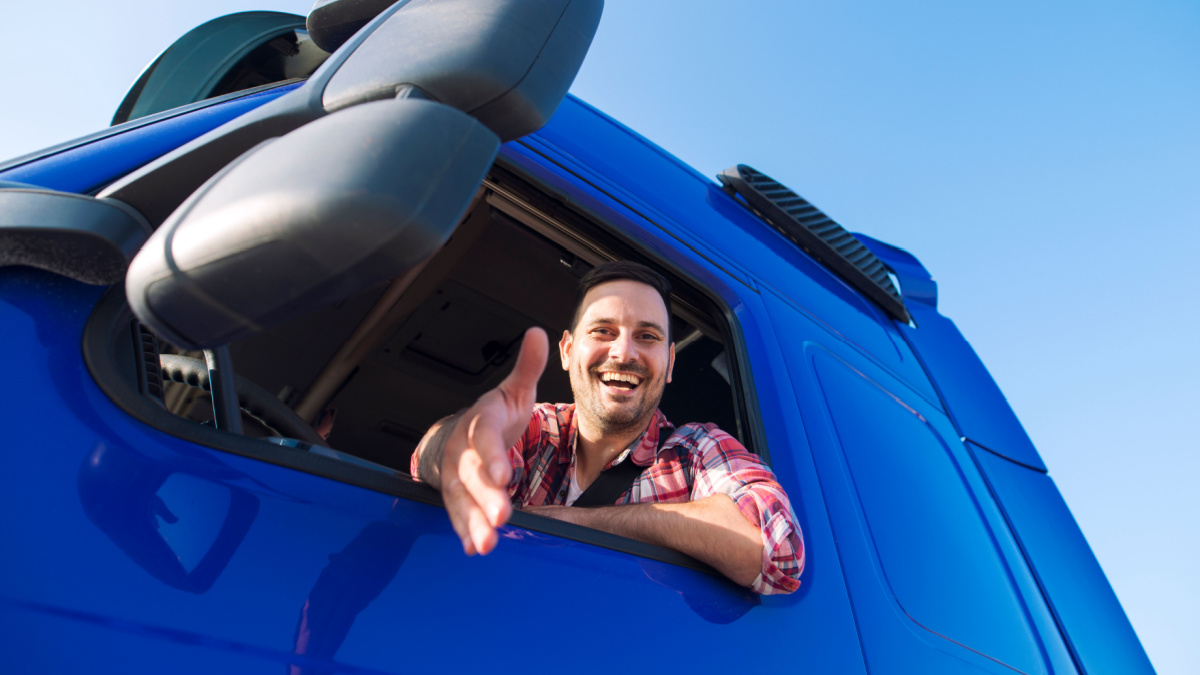 Truck drivers job openings. Truck driving careers. Middle aged professional trucker driver sitting in his vehicle cabin and giving a shaking hand to new recruits. Drivers wanted.