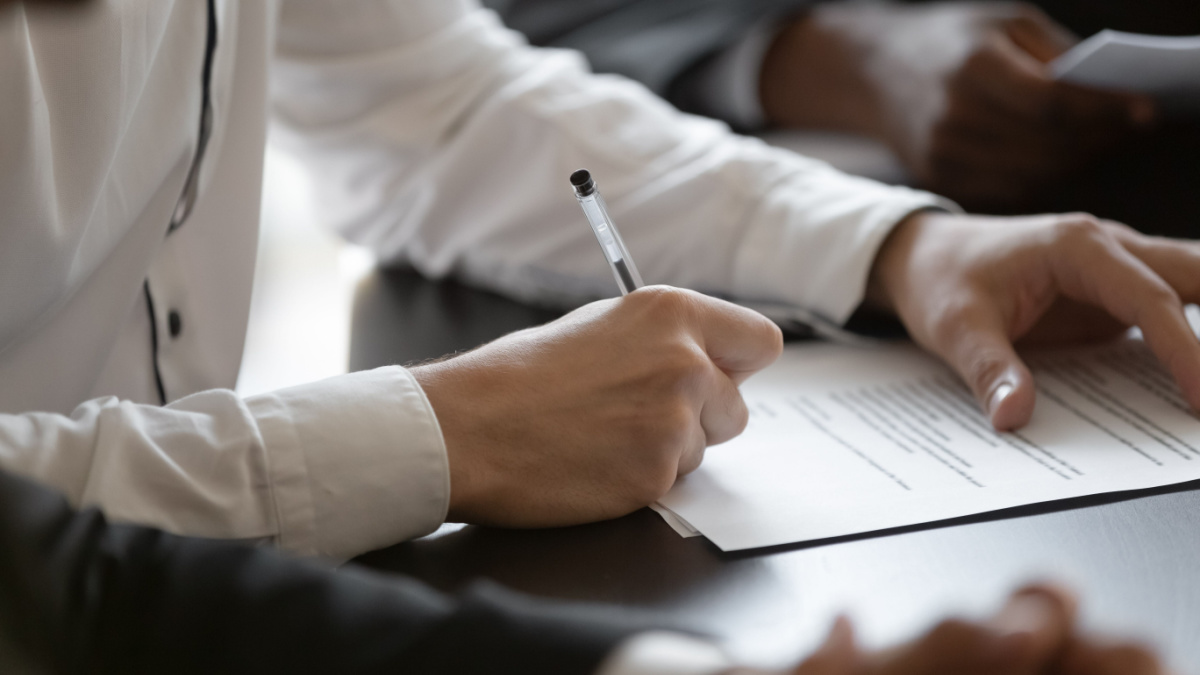 Close up young male employee manager customer hands signing paper contract after checking.
