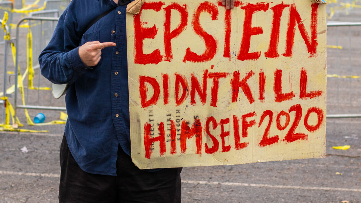 Man at Trump rally holding a sign that reads Epstein Didn't Kill Himself 2020
