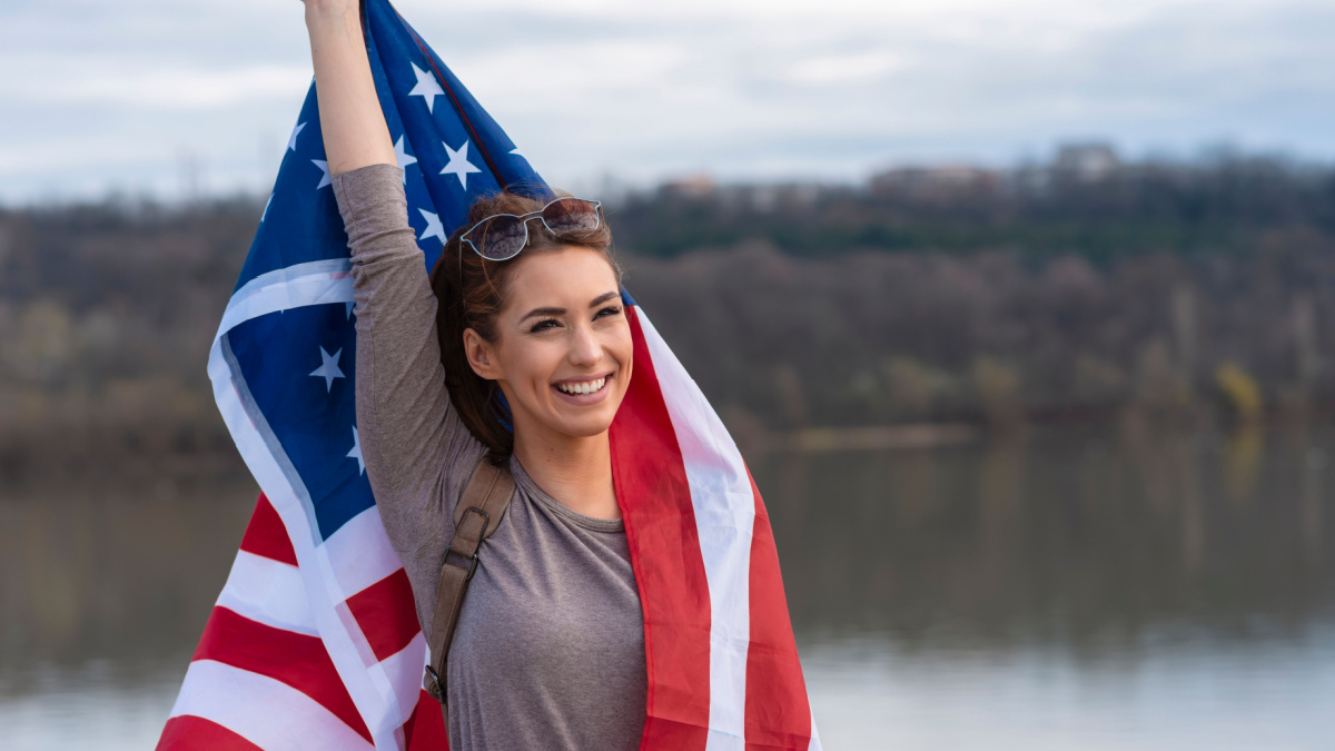 Pretty young woman holding american flag.