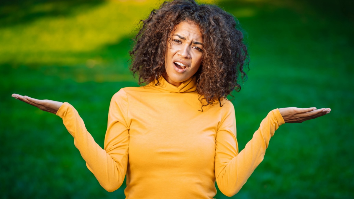 Unsure african american woman shrugs her arms, makes gesture of I don't know, care, can't help anything.