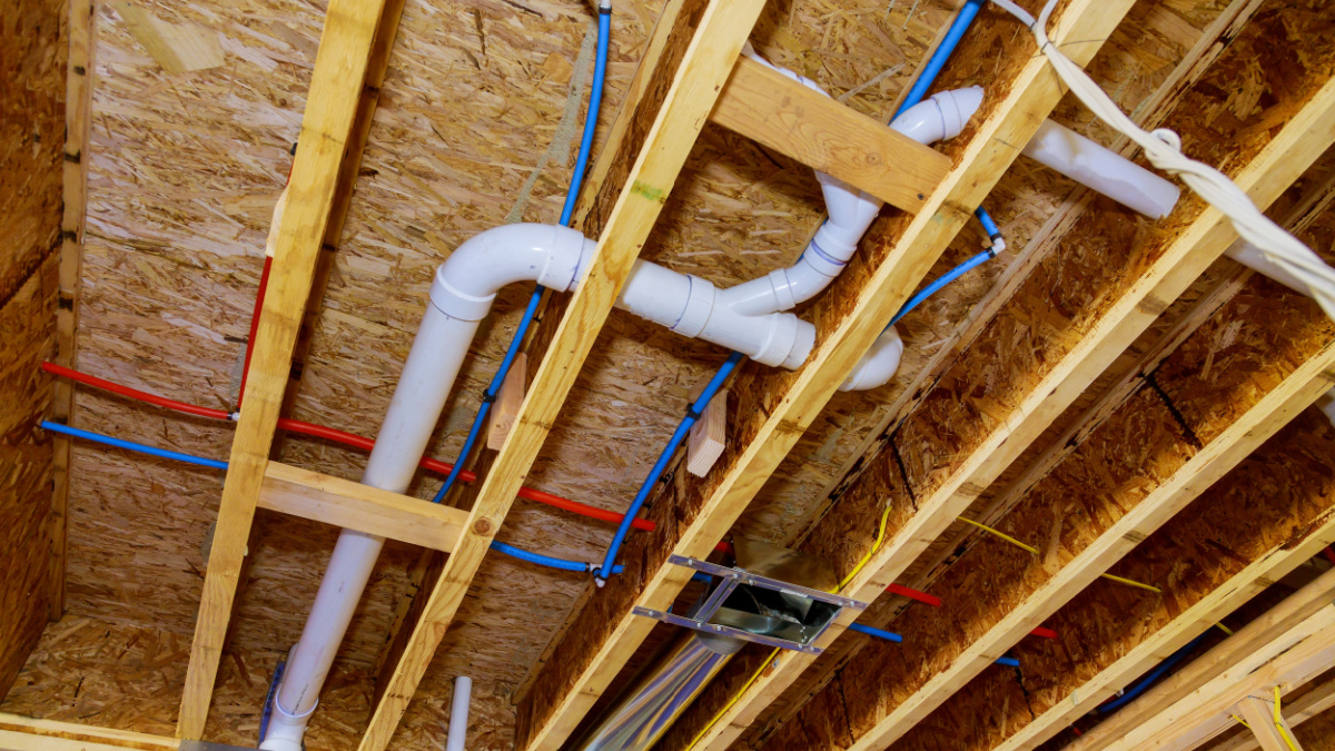 Home construction with hot red and cold blue pex pipe layout in pipes and exposed beams.