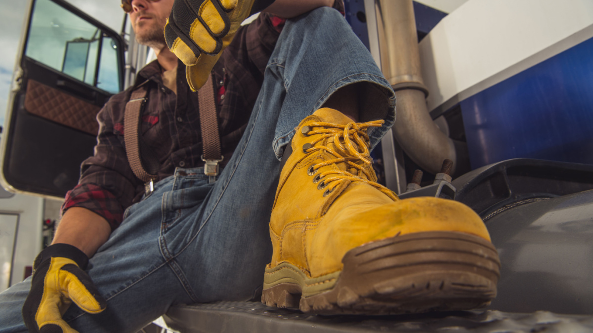 Caucasian Male Trucker Sitting Outide Of His Vehicle And Relaxing During Break.