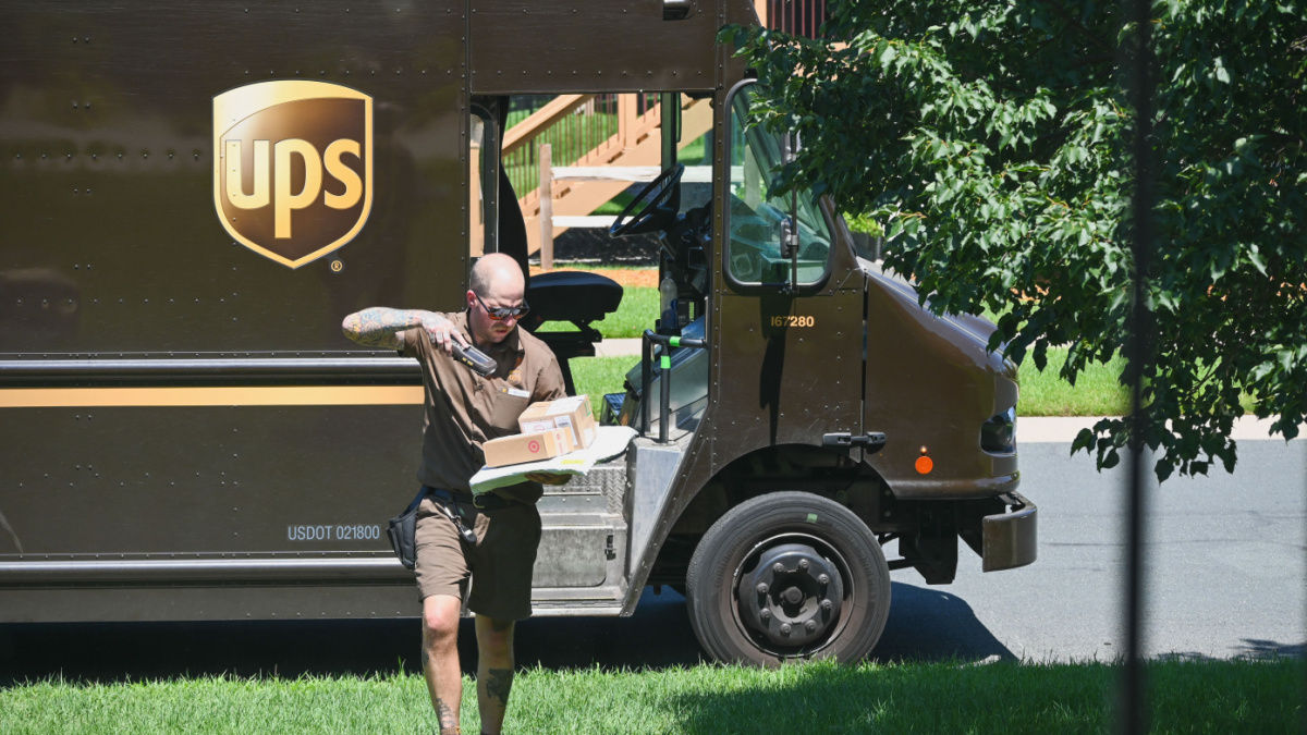 An UPS delivery driver scans a package before leaving the order at a house.