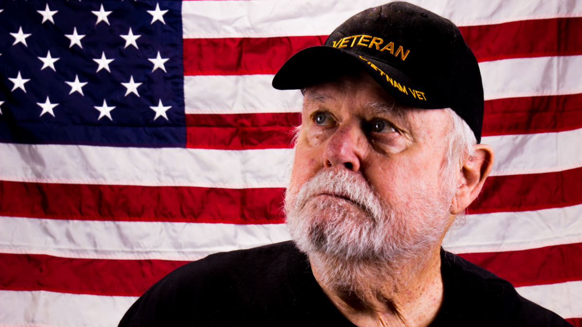 Vietnam Vet With Rough Beard Looking Up With American Flag Background.