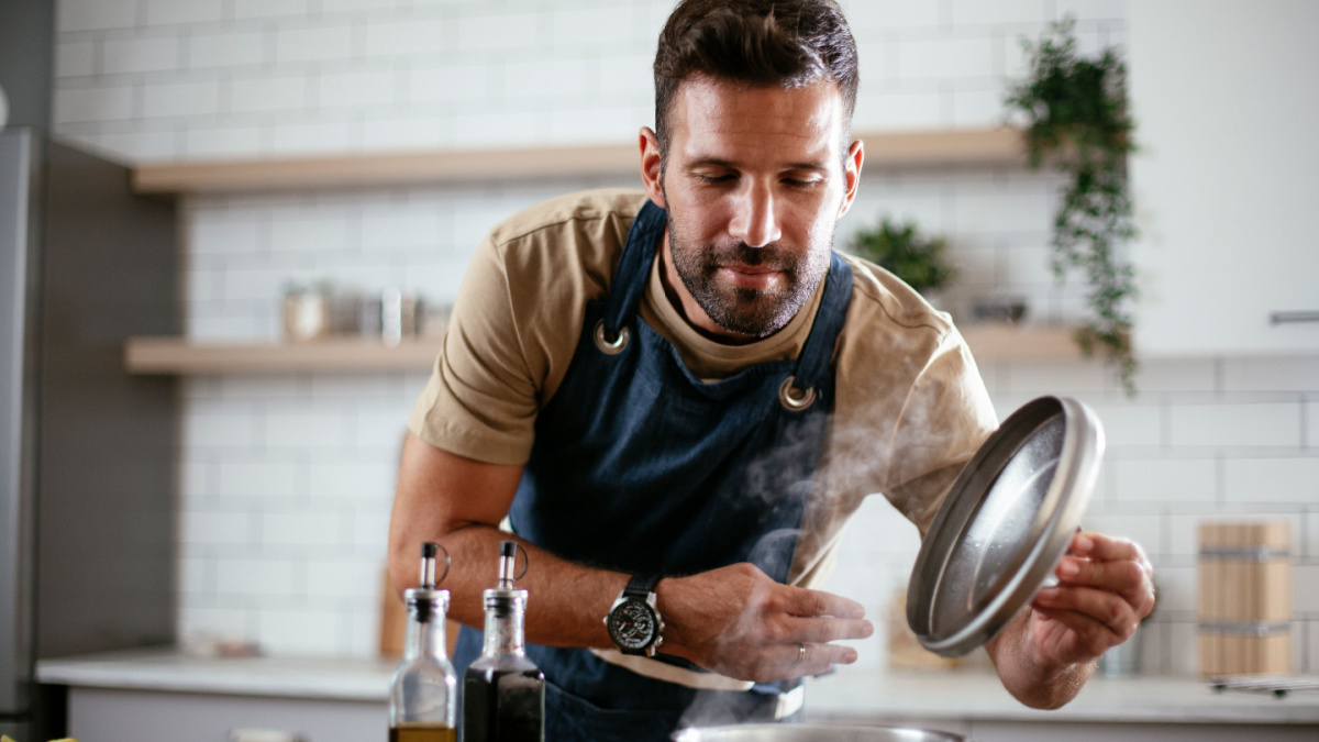 Happy man in kitchen. Young man preparing delicious food.