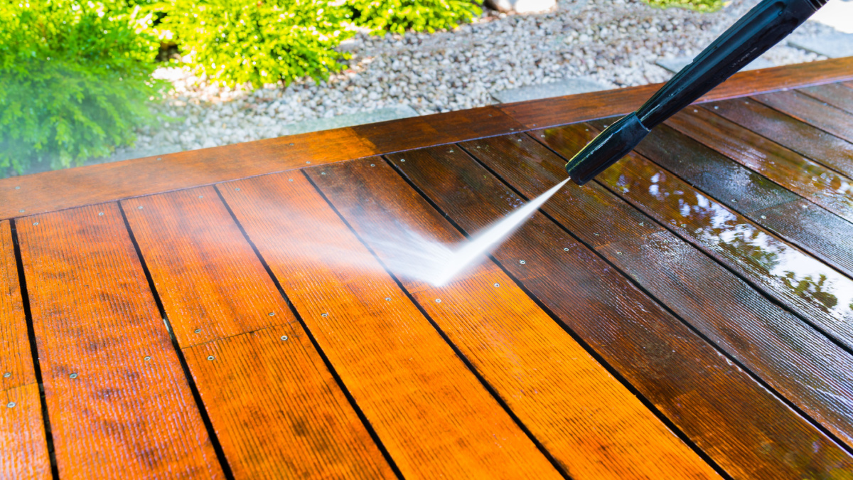 cleaning the terrace with a pressure washer - high-pressure cleaner on the wooden surface of the terrace - very shallow depth of field - sharpness on the terrace board under a stream of water.