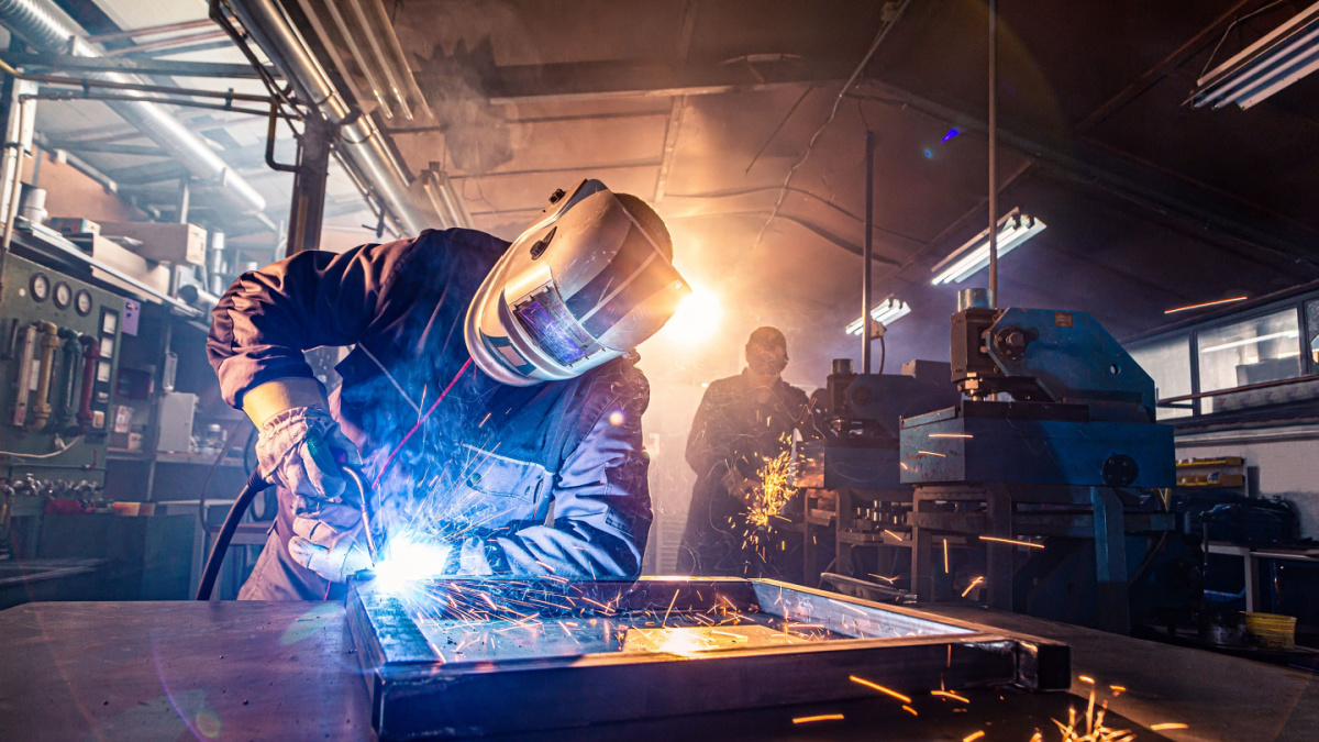 The two handymen performing welding and grinding at their workplace in the workshop, while the sparks 