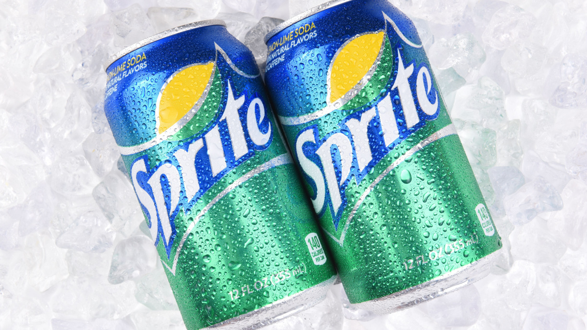 Two Sprite Cans on a bed of ice with condensation. Sprite is a lemon lime soft drink from the Coca-Cola Comapny.