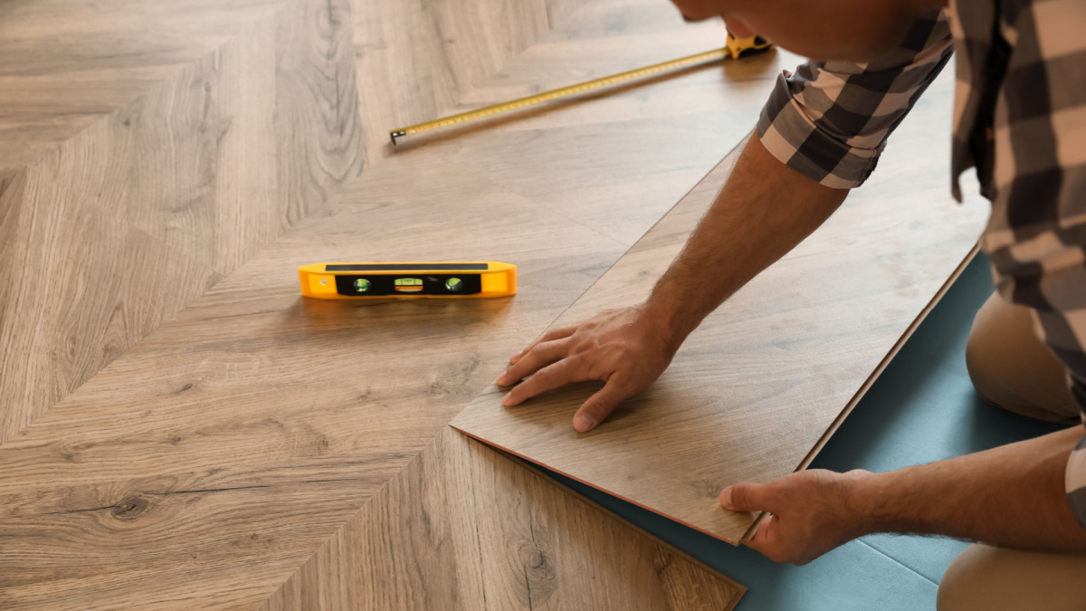 Professional worker installing new parquet flooring indoors, closeup
