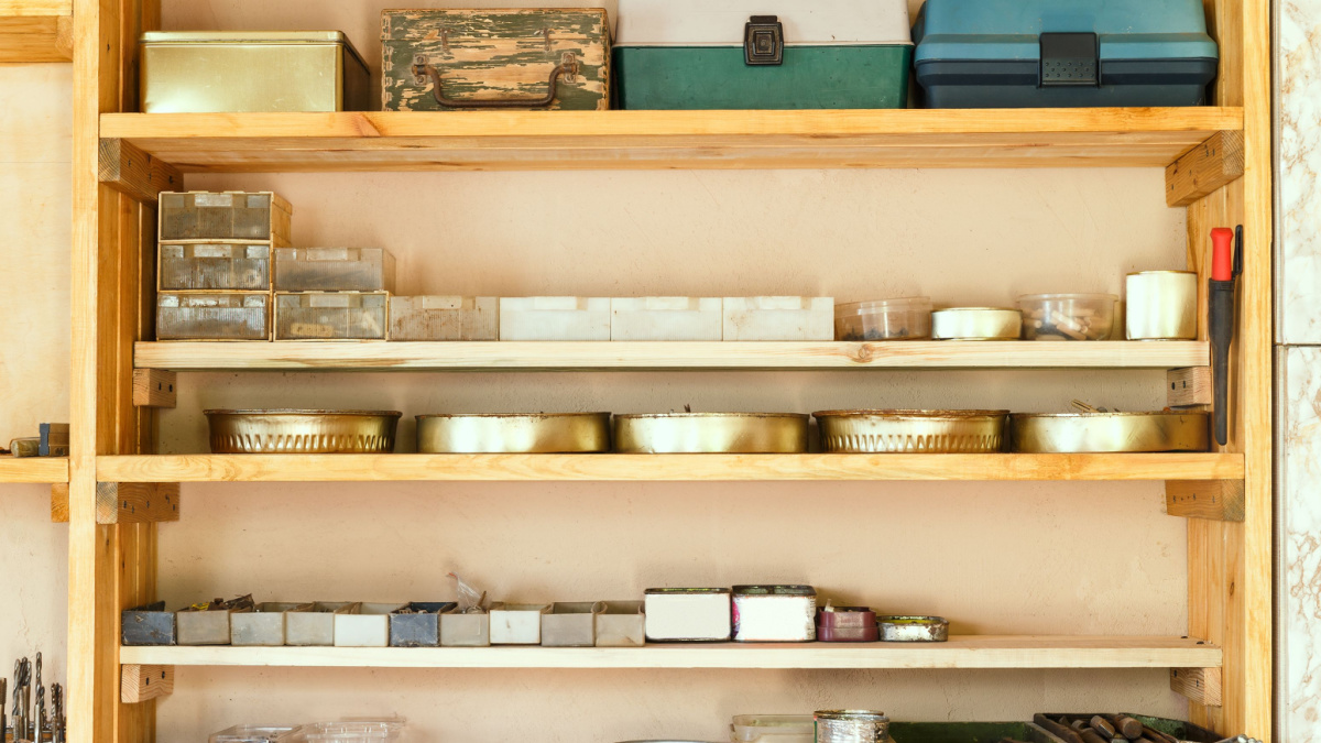 Wooden shelving units with different furniture in custom workroom. Boxes with various accessories and tools are placed on the shelves.