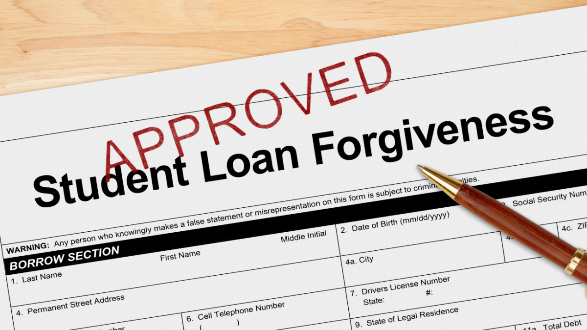Student Loan Forgiveness application approved with pen on a wood desk