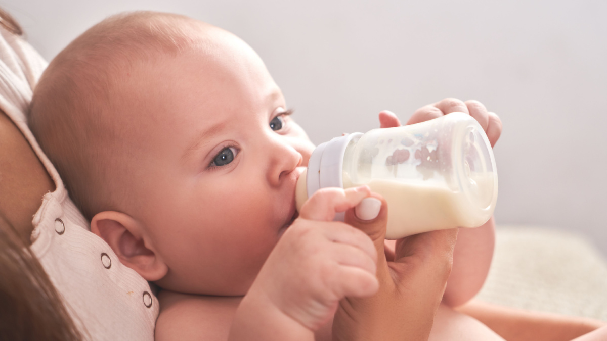 Mom feeds her happy child son baby milk powder, baby bottle