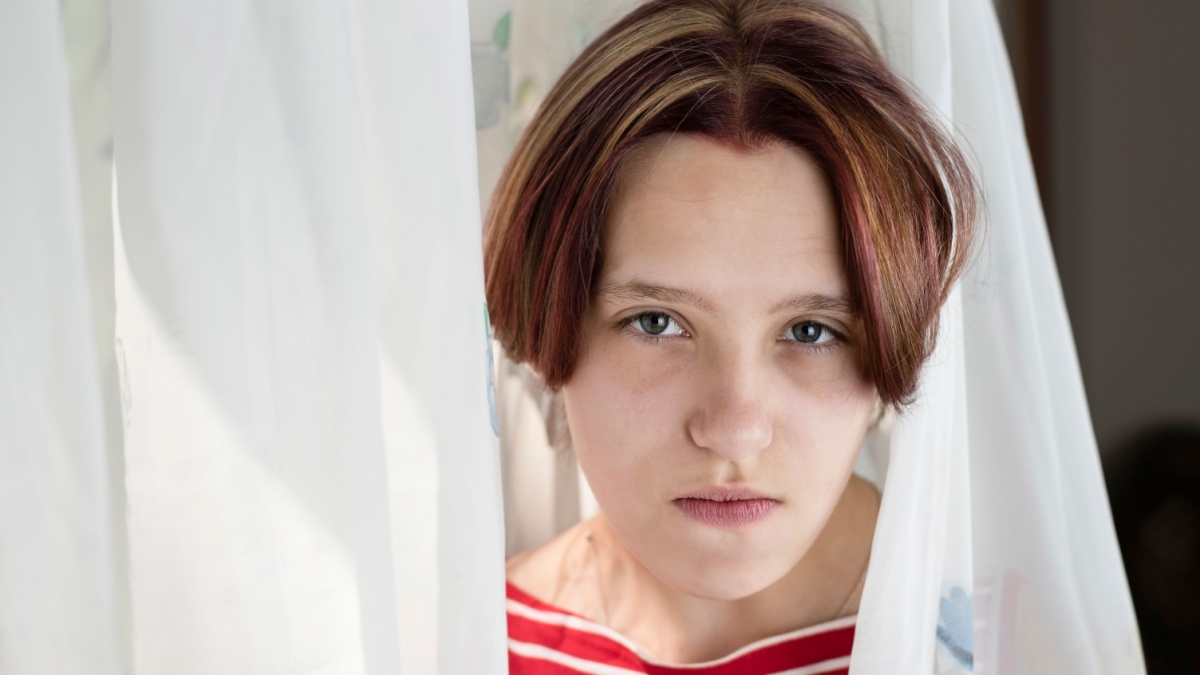 Portrait of a teen girl with emotions of sadness and anger on her face. The girl has begun adolescence and it is often difficult for her to talk to adults or friends and she tries to be calm.
