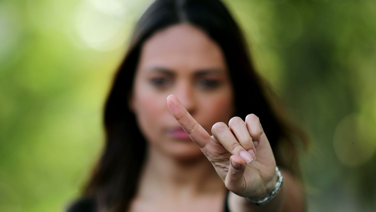 Woman annoyed making stop sign with hand, saying no, expressing defense or restriction.