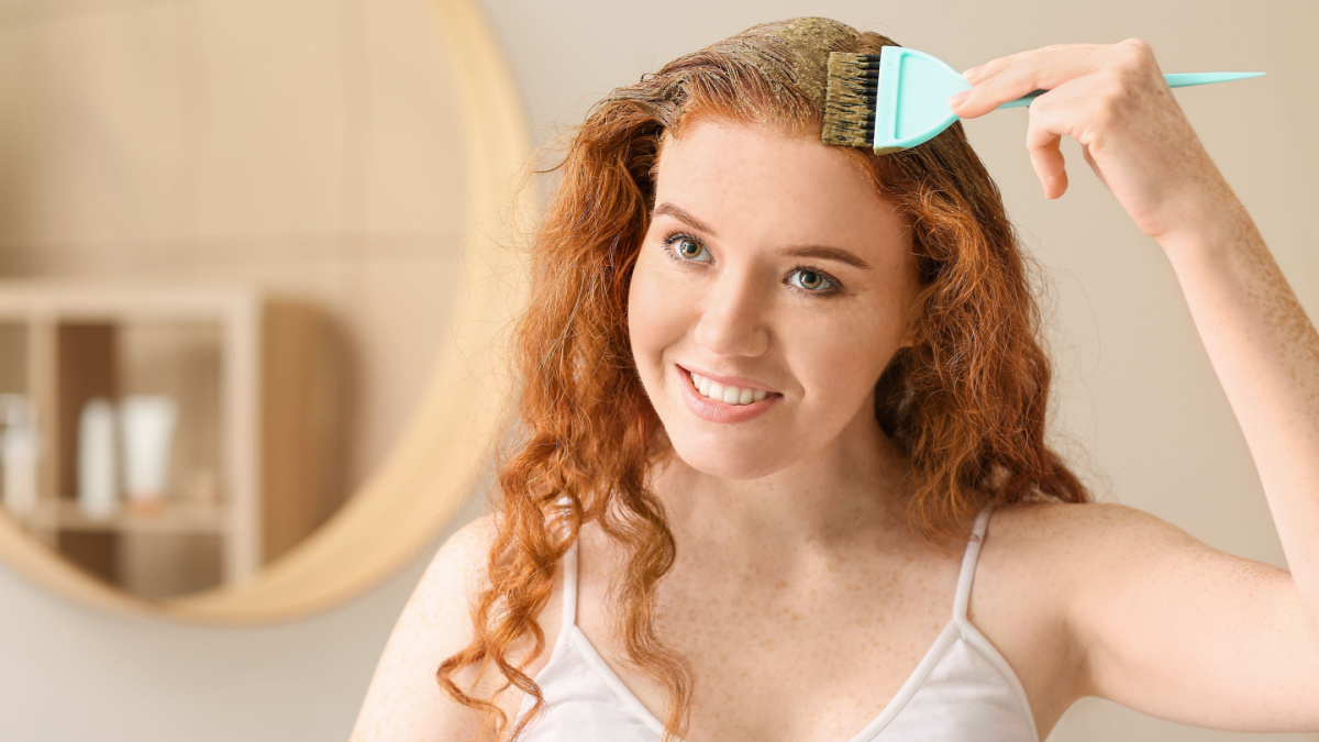 Young woman using henna hair dye at home.